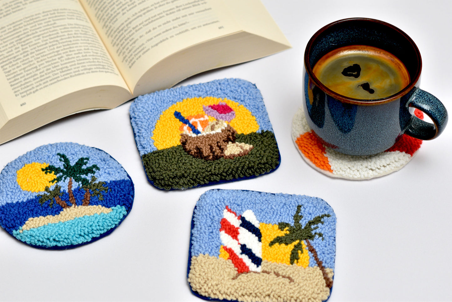 Set of coasters with beach designs on a table with a book and mug.