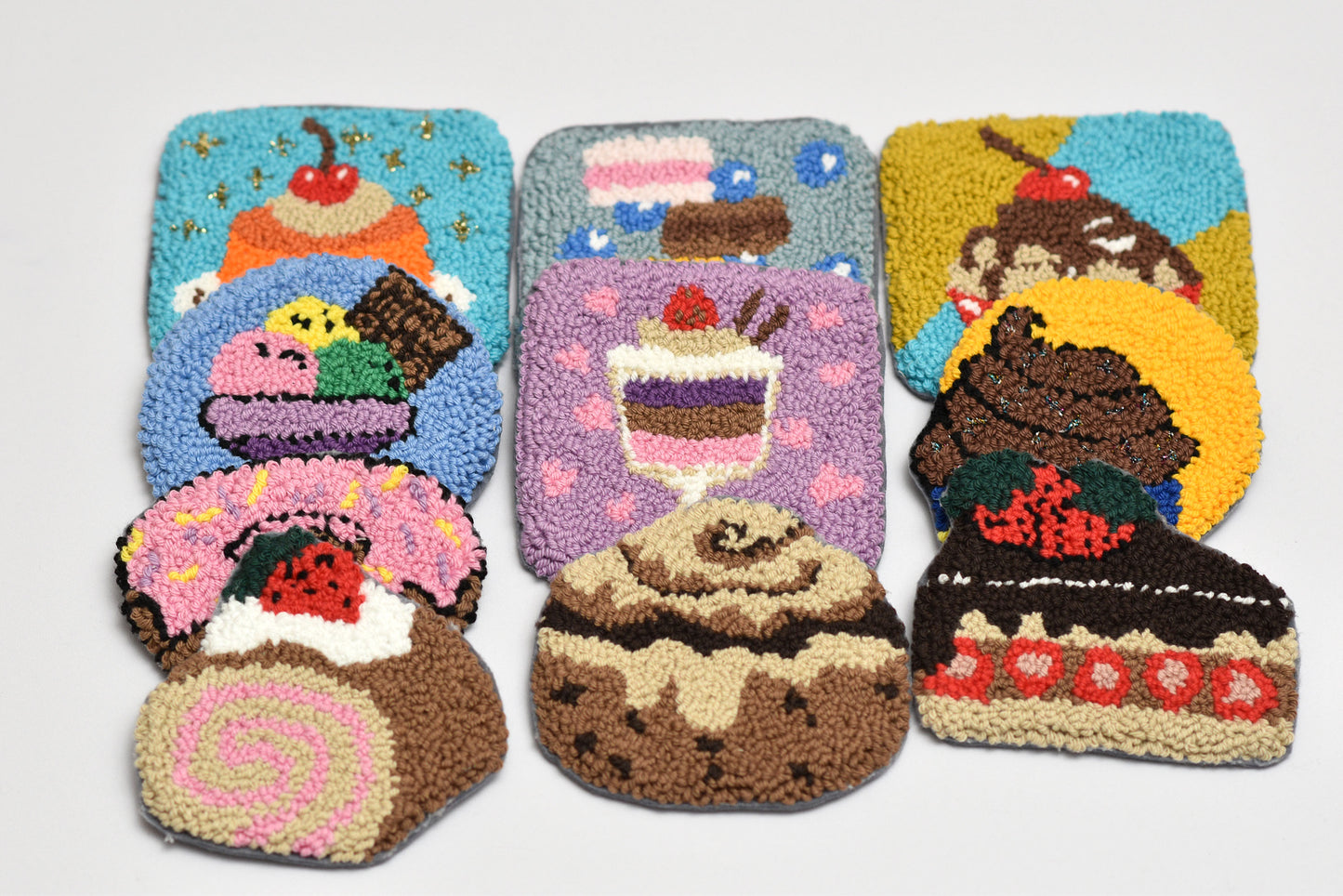 Set of ten colorful rug hooks shaped like desserts on a white background