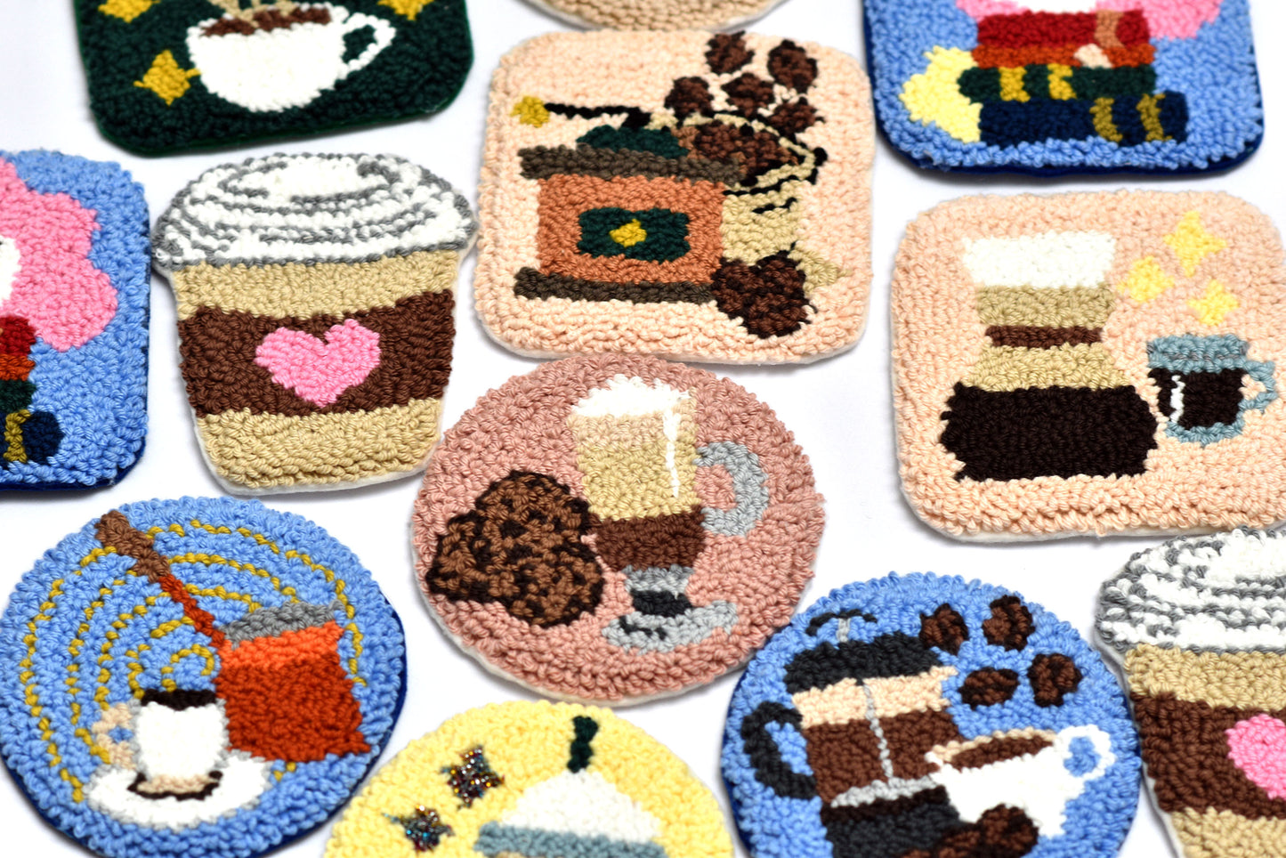 Collection of colorful punch needle coasters with coffee-themed various designs on a white background