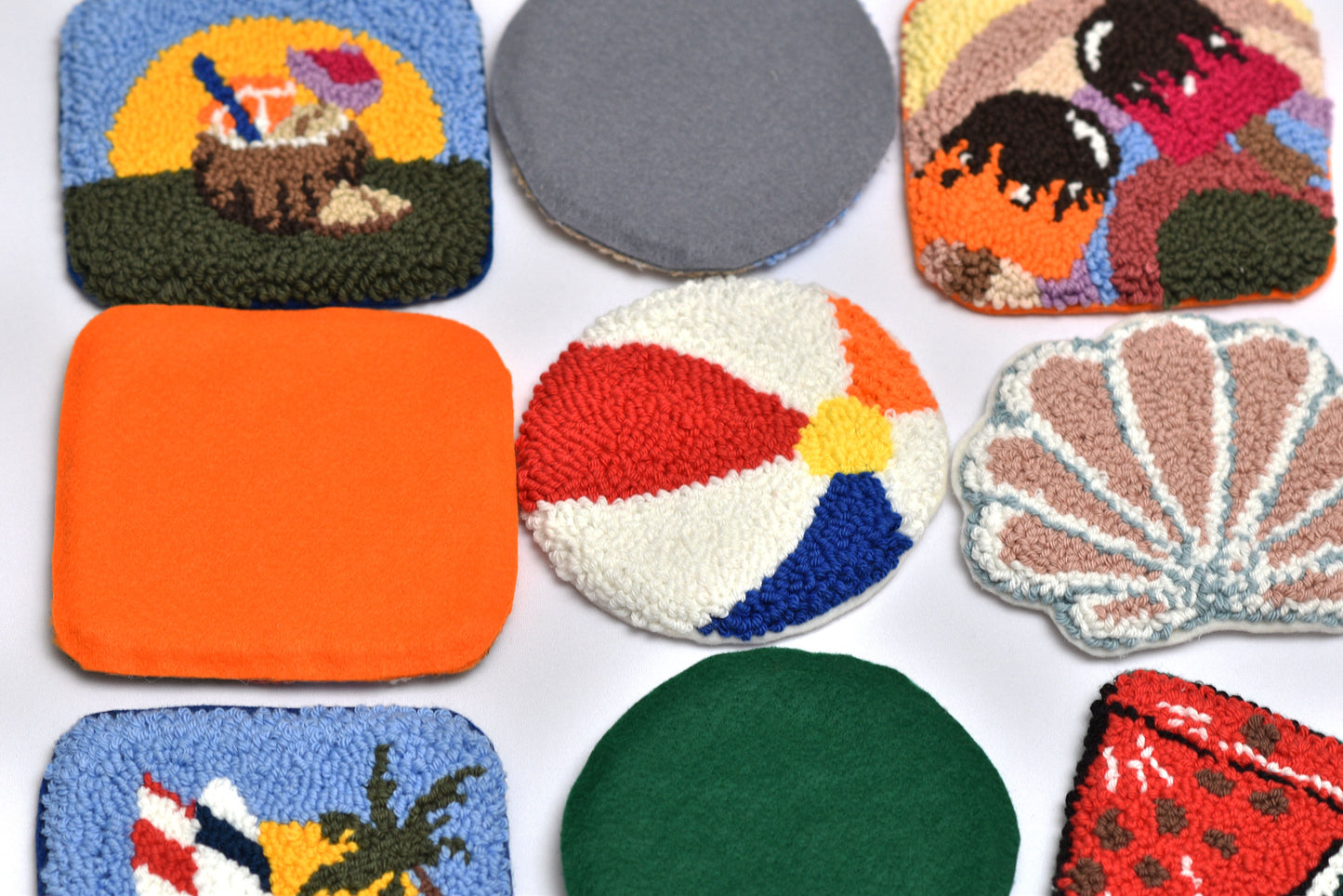 Collection of colorful embroidered coasters with various designs on a white background