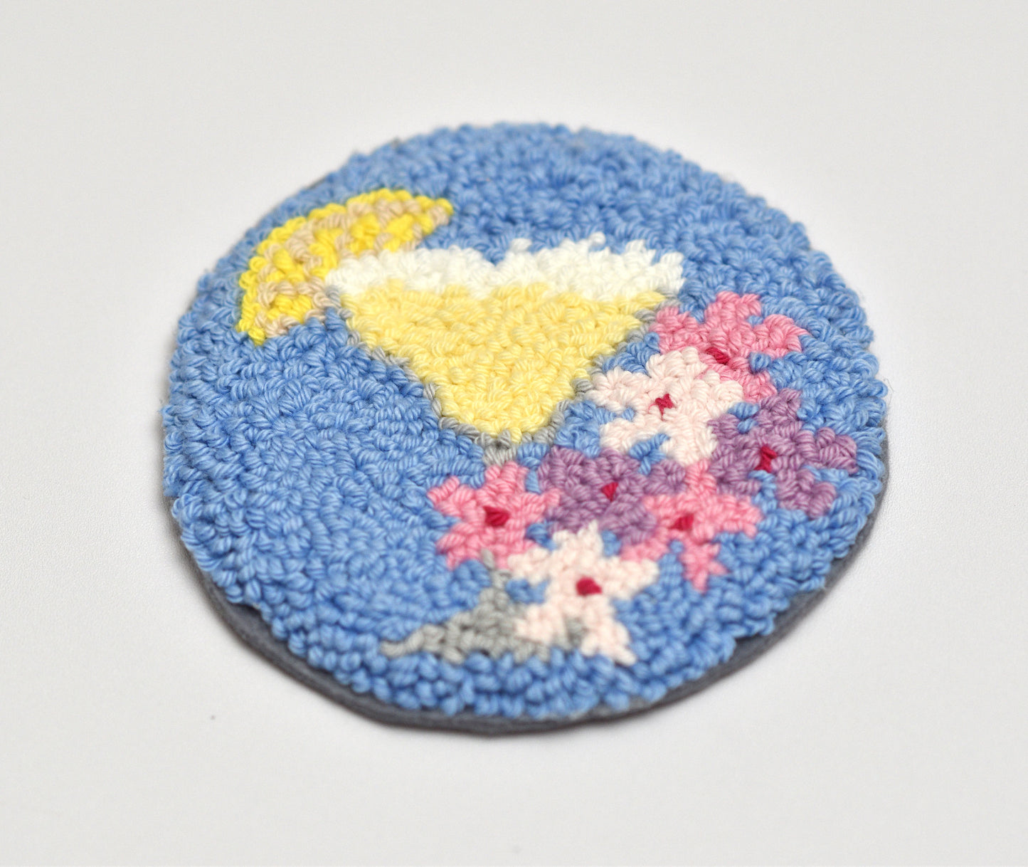 Round blue mug rug with a Margarita cocktail and yellow lemon slice and pink flowers design on a white background