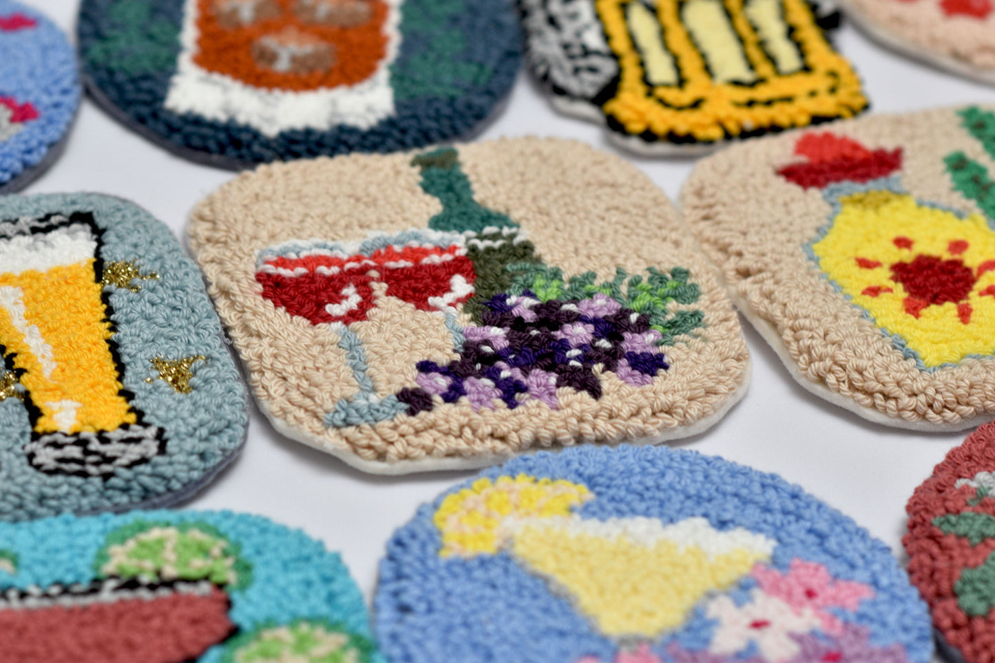 Collection of colorful embroidered coasters with various designs on a white surface.