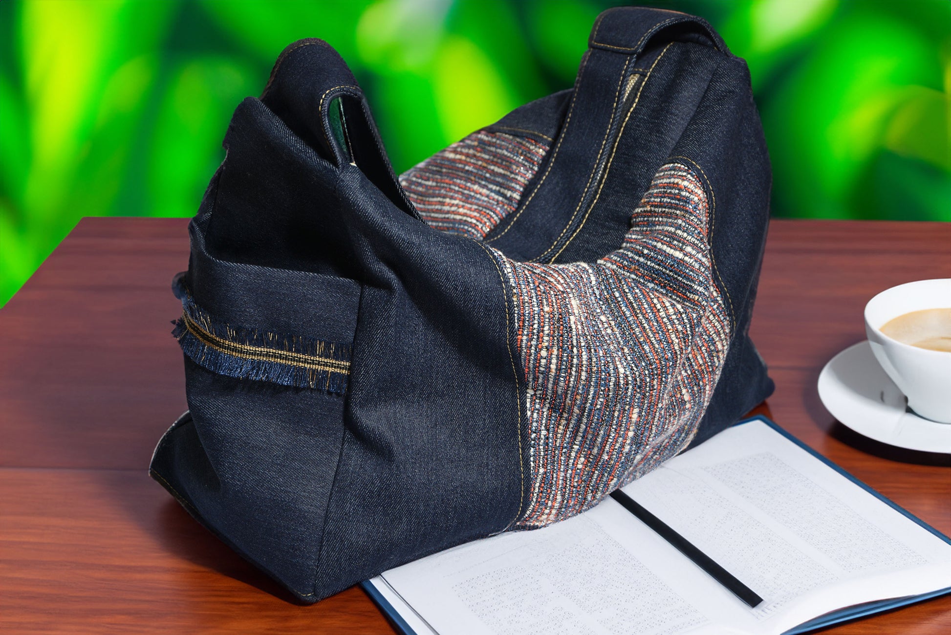 Black and patterned fabric bag on a wooden surface with a blurred green background