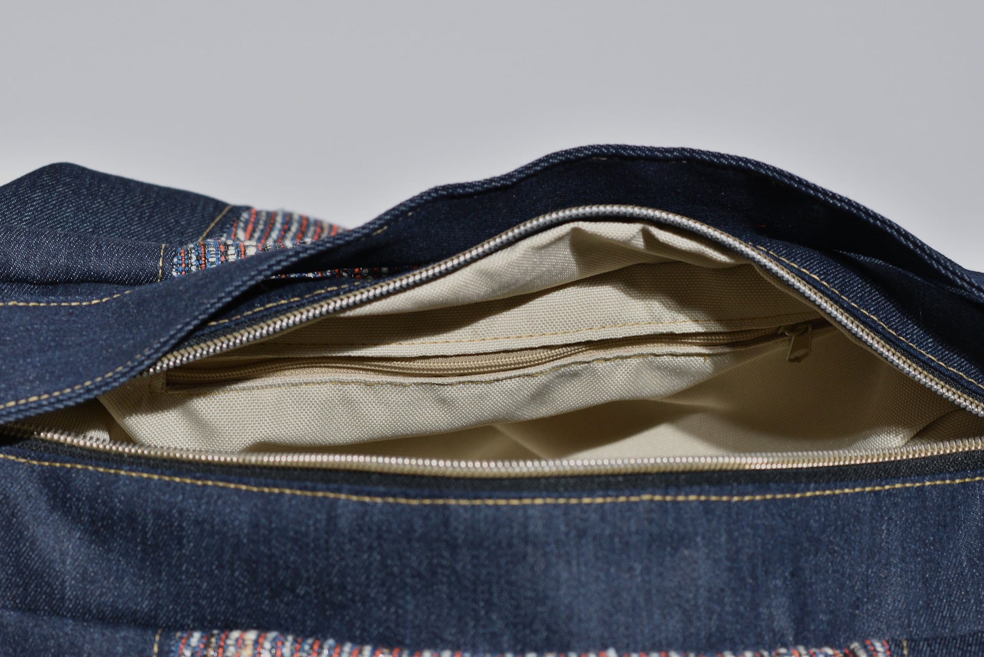 Open denim bag with beige interior on a gray background